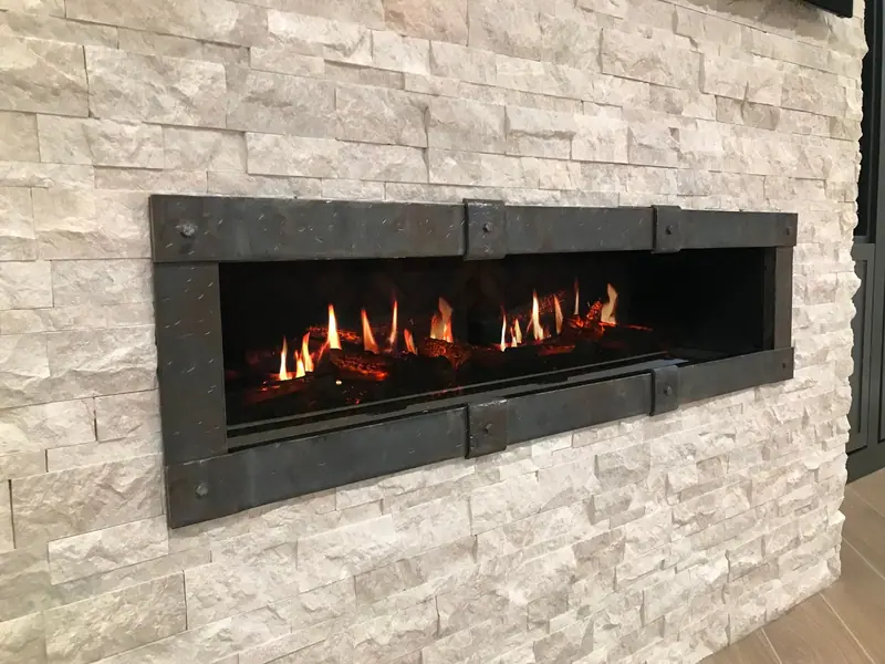 Linear fireplace set into a white stacked stone wall