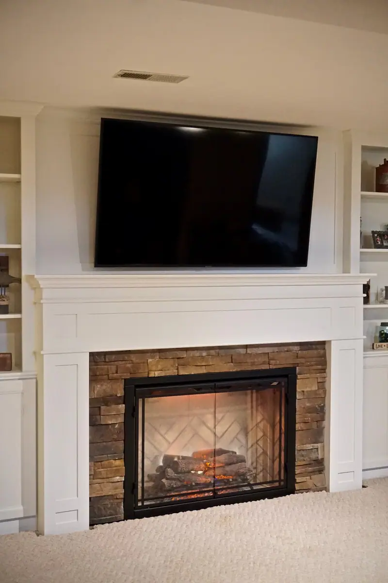 Fireplace with white mantel and television above