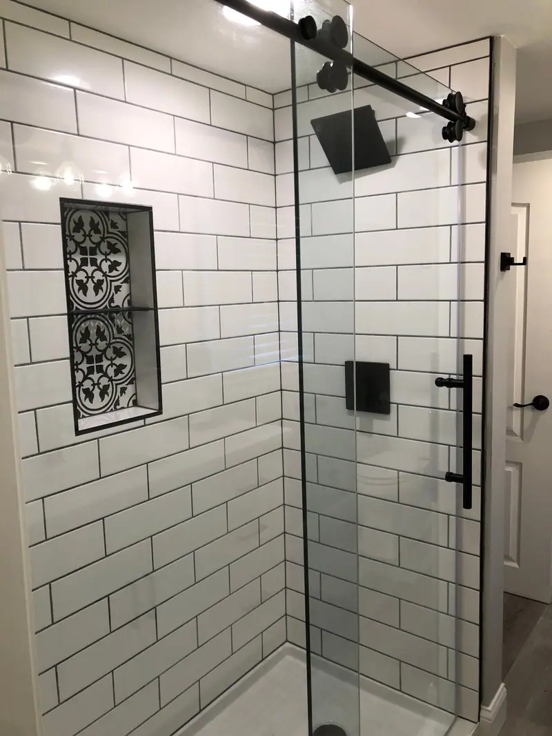 Walk-in shower with white subway tile and black glass door hardware