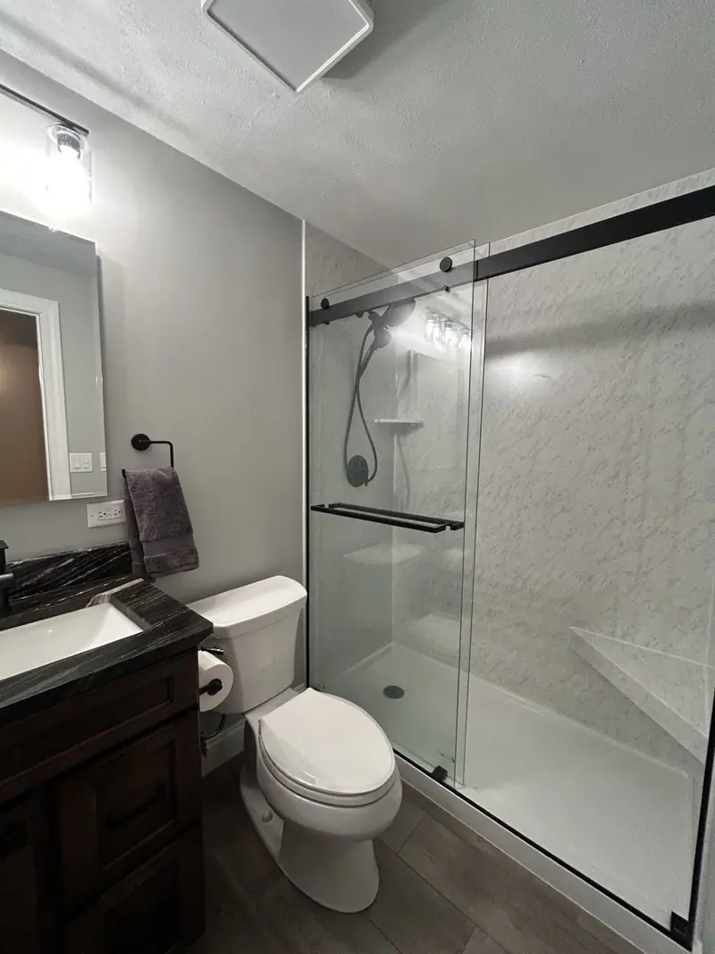 Shower with glass slider door and dark vanity
