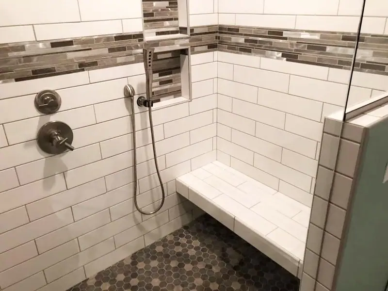 Subway tile shower with bench seat and pebble floor