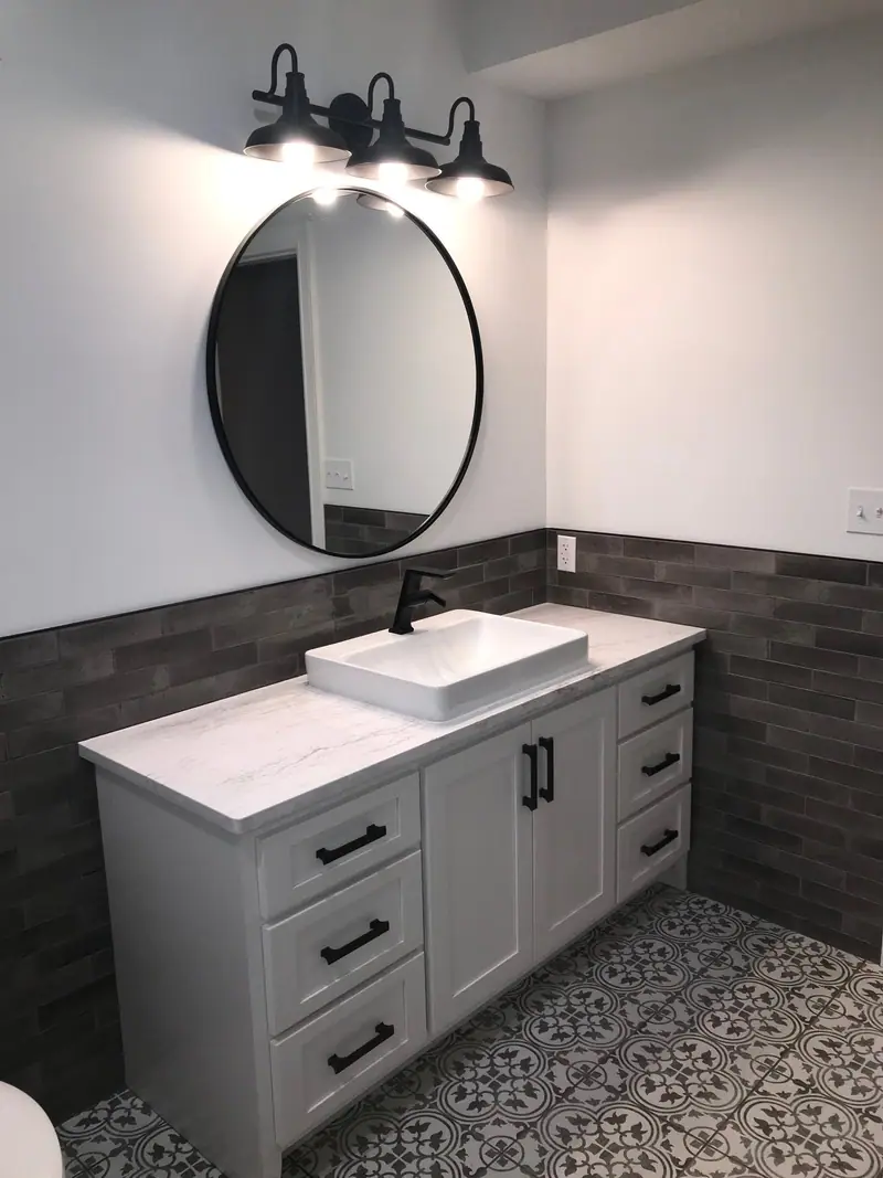 Vessel sink vanity with round mirror and tile wainscot