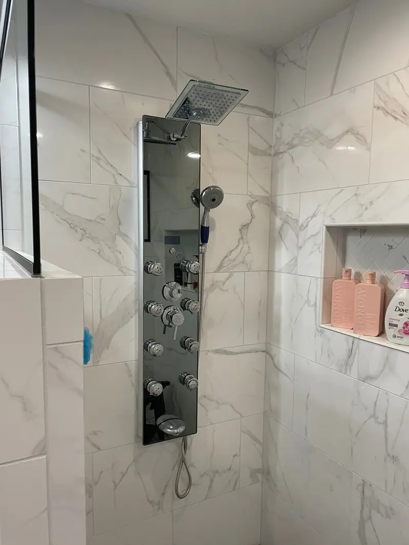 Marble-look tile shower with body spray panel and niche