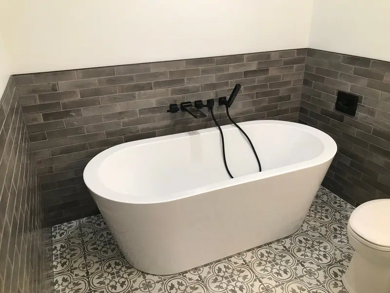 Freestanding tub with matte black floor-mount faucet and patterned tile