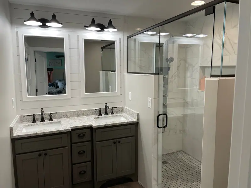 Double vanity with framed mirrors and glass shower enclosure