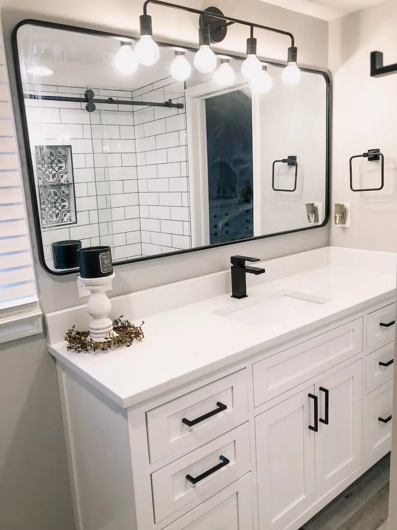 White vanity with black faucets and mirror