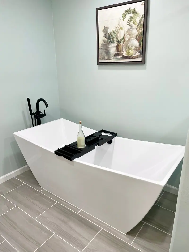 Freestanding tub with floor-mount faucet beside a window