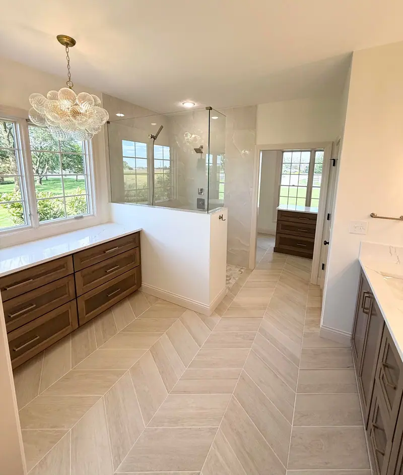 Primary bathroom with wood vanity and herringbone tile floor