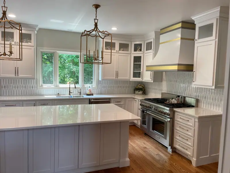 White custom kitchen with brass-banded range hood and lantern pendants