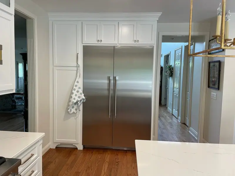 Built-in refrigerator surrounded by white cabinetry