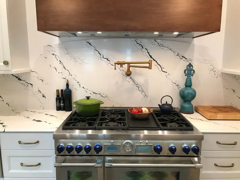 Marble slab backsplash with pot filler above a professional range