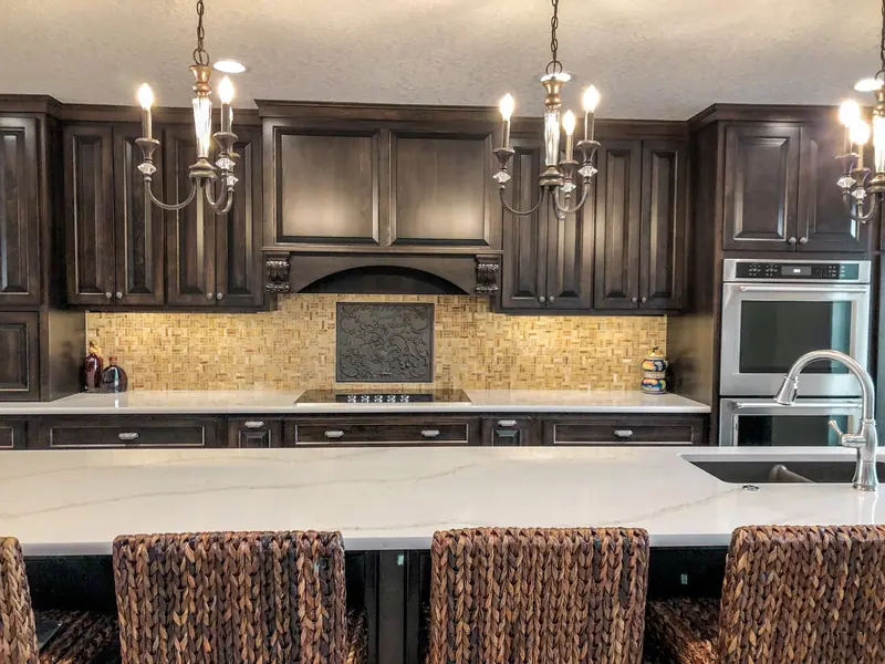 Dark wood kitchen with chandeliers and a long quartz island