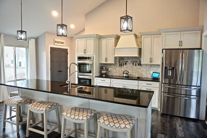 Kitchen with dark island countertop, pendant lights and stainless appliances