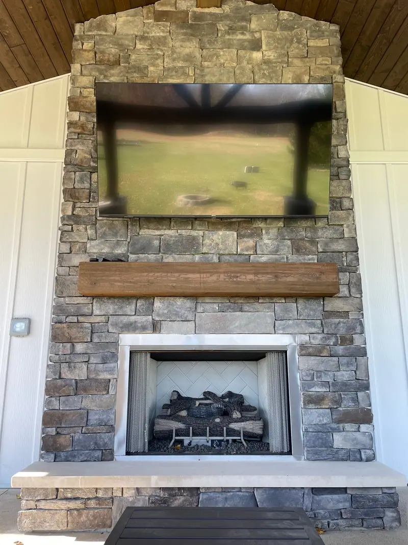Outdoor stone fireplace with wood mantel
