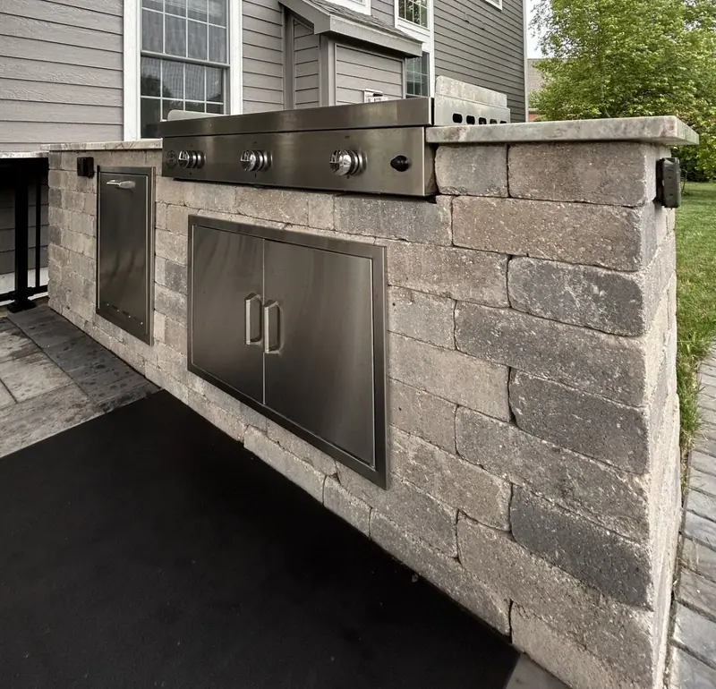 Outdoor kitchen island with stainless grill and storage doors